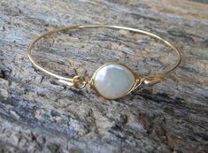 A gorgeous freshwater pearl has been wire wrapped and attached to a non-tarnishing gold-plated brass wire to create this elegant bangle. This bangle looks great stacked with other bangles in my shop or worn alone, and is the perfect bridesmaid gift. This is a closed bangle and must be able to slide over the widest part of your hand. To determine your size, please measure from your pinky to index finger, choose a size below, and write your size in the notes to seller. If no size is specified, a s Gold And Pearl Jewelry, Keshi Pearl Bracelet, Gemstone Bangle Bracelets, Pearl Bangle Bracelet, Mother Of The Groom Gift, Wedding Jewelry For Bride, Mother Of The Bride Gift, Bridesmaid Pearls, Gemstone Bangle