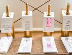 four wine bottles are sitting on the table with their tags in front of them that say sip, drink, and celebrate