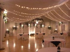 a banquet hall with tables and chairs covered in lights