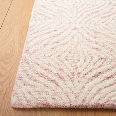 a white and red rug on top of a wooden floor