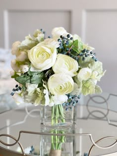 a vase filled with white flowers on top of a glass table