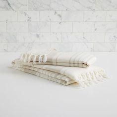 three white towels stacked on top of each other in front of a marble tile wall