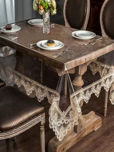 a wooden table topped with plates and chairs next to a vase filled with flowers on top of a hard wood floor