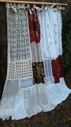 several different types of lace hanging on a clothes line with leaves and bushes in the background