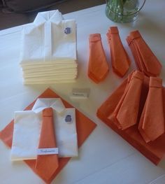 there are many folded orange and white ties on the table next to some napkins