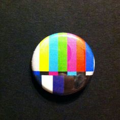 a button that has been placed on a table with the colors of tv test pattern