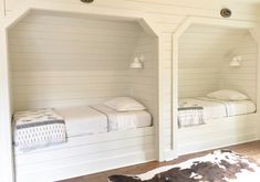 two twin beds in a white room with cow hide rug on the floor and wood floors