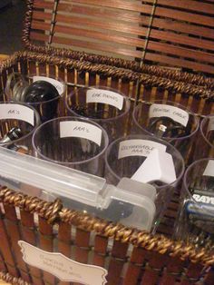 several wine glasses in a wicker basket with labels on the lids and tags attached to them