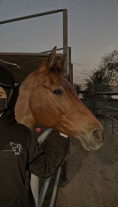 a man in black jacket petting a brown horse