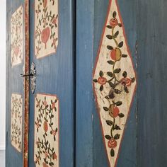 an old blue painted cabinet with flowers and leaves on the door side, in a room