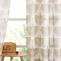 a basket sitting on top of a wooden table next to a window covered in curtains