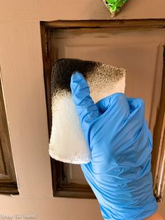 a person in blue gloves is cleaning a door with a sponge and cloth on it