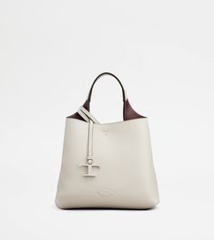 Flowing lines and elegant play of volumes characterize this bag in hammered leather, with flat handle and a removable shoulder strap. The interior features two compartments separated by a zipped pocket. A contemporary creation enhanced by distinctive iconic detailing, such as metal T Timeless pendant and T stitching. Tan Calf Leather Bags With Silver-tone Hardware, Tan Shoulder Bag With Palladium Hardware In Calf Leather, Tan Calf Leather Shoulder Bag With Palladium Hardware, Formal Tan Bags With Silver-tone Hardware, Business Shoulder Bag In Tan With Silver-tone Hardware, Tan Shoulder Bag With Palladium Hardware For Shopping, Modern Tan Bags With Detachable Handle, Modern Tan Shoulder Bag, Timeless Tan Textured Leather Bags