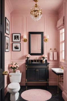 a bathroom with pink walls, black vanity and gold accents on the wall above the toilet