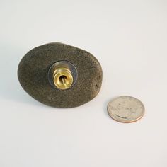 a coin is sitting next to a small light fixture on a white surface with a hole in the middle