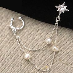 Inspired by the goddess of love and beauty who was born of the sea... The Aphrodite Pearl Earring is three 4mm freshwater pearls on a delicate chain that connects a glittering star to an ear cuff. The goddess was supposedly born in Cyprus and was celebrated with festivals at midsummer. We love how this delicate charmer creates a goddess vibe. The post back is surgical steel and the gold metal is brass plated in silver. Pearls are genuine freshwater pearls. Stones are cubic zirconia. Set of two e Elegant Star-shaped Cartilage Earrings, Silver Star-shaped Pearl Jewelry, Star-shaped Silver Pearl Jewelry, Silver Pearl Drop Ear Cuff For Wedding, Wedding Silver Ear Cuff With Pearl Drop, Pearl Single Ear Cuff As A Gift, Elegant Sterling Silver Star Cartilage Earrings, Dream Earrings, Goddess Of Love And Beauty