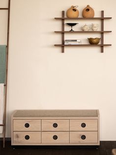 a shelf with two vases on top of it next to a chest of drawers