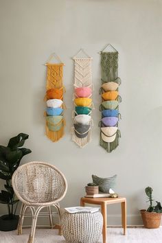 three woven wall hangings are hung on the wall above a wicker chair and small table