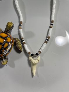 two necklaces that have different types of beads and animals on them, one with a turtle's head hanging from it