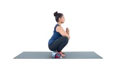 a woman kneeling down on a yoga mat with her hands clasped in front of her chest