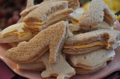 several sandwiches are stacked on a plate with grapes in the backgroung behind them