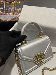 D.G Small Devotion Bag In Plain Silver For Women 7.5in/19cm DG Rep 1:1 Size: 13 x 19 x 4.5 cm / 5.1 x 7.5 x 1.8 inches (Length x Width x Height) Top handle and detachable shoulder strap Front flap with bejeweled branded heart hand-tooled from a metal alloy with pearl inlay Concealed magnetic fastening and customized heart Interior with flat pocket Item comes with its own special dust bag and packaging Includes box, dust bag. This product is of the best quality. Dg Bag, Louis Vuitton Shirt, Pearl Inlay, Gucci Gg Marmont, Heart Hands, Evening Clutch Bag, Tote Backpack, Belts For Women, Satchel Bags