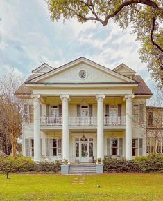 a large white house sitting on top of a lush green field