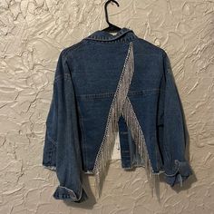 a denim jacket with fringes hanging on a wall