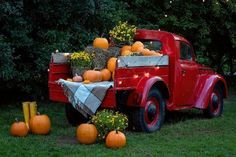 an old red truck with pumpkins in the back