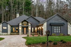 a house that is in the middle of some trees and grass with a driveway leading to it