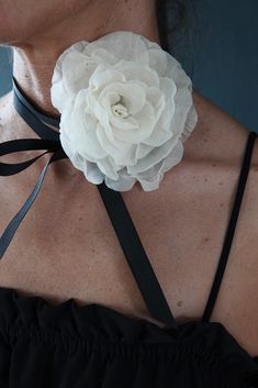 a woman wearing a white flower on her neck