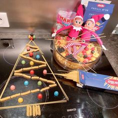 an elf is sitting in front of a christmas tree made out of candy