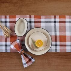 an orange slice on a plate next to other plates and utensils sitting on a checkered table cloth