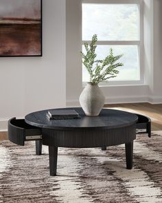 a black table with a white vase on it and a rug in front of it