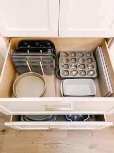 an open drawer with dishes and pans in it