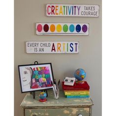 there is a dresser with some art on it and two signs that say creativity, every child is an artist