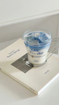 an open book on top of a table next to a bowl of ice and water