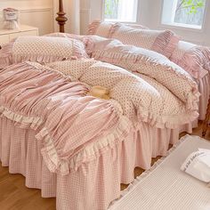 a bed with pink ruffled bedspread and pillows