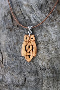 an owl necklace is sitting on top of a tree stump with the letter s in it's eyes