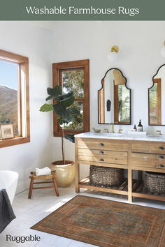 a bathroom with two sinks, mirrors and rugs in front of the tub area