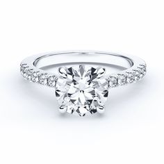 a round brilliant cut diamond ring with pave set diamonds on the shoulders and sides