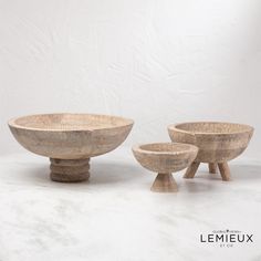 three wooden bowls sitting next to each other on top of a white tablecloth covered floor