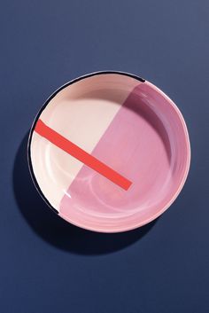 a pink and white plate with a red line on the side, against a blue background