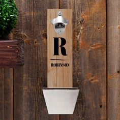 a bottle opener mounted to the side of a wooden wall next to a potted plant