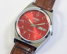 Vintage Seiko 5 Automatic Japan Mens Wrist watch red arabic dial mechanical day date stainless steel gift for men for him This restored vintage watch has undergone professional cleaning, polishing, servicing, and oiling and is now ready to use  . Watch case diameter is 36mm without the crown and the lug size is 18mm . The watch features a new aftermarket dial, hands and band/strap, while retaining its original case and movement. . Provided pictures are an integral part of the item description, capturing every detail for your assessment. . Any defects not mentioned in the description but can be seen in the pictures will be considered as described. . Mechanical watches naturally exhibit slight variations in timekeeping. Please allow for a few minutes' deviation per day. . Watch has been test Seiko 5 Automatic, Steel Gifts, Seiko 5, Professional Cleaning, Wristwatch Men, Mechanical Watch, Watch Case, Gift For Men, Vintage Watches