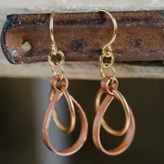 two pairs of earrings hanging from a hook on a piece of wood with hooks attached to it