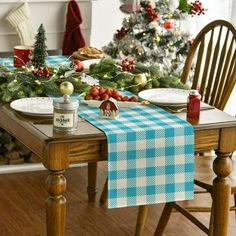 a dining room table set for christmas with blue and white checkered table cloth on it