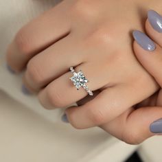 a woman's hand holding a ring with a diamond on the middle and two fingers