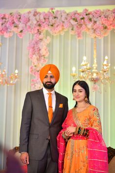 a man and woman standing next to each other in front of a floral decorated wall