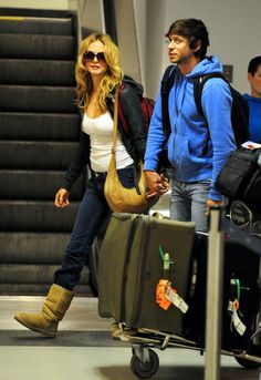 a man and woman walking through an airport with luggage